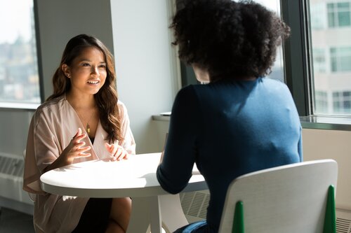 Zwei Frauen sitzen an einem runden Tisch