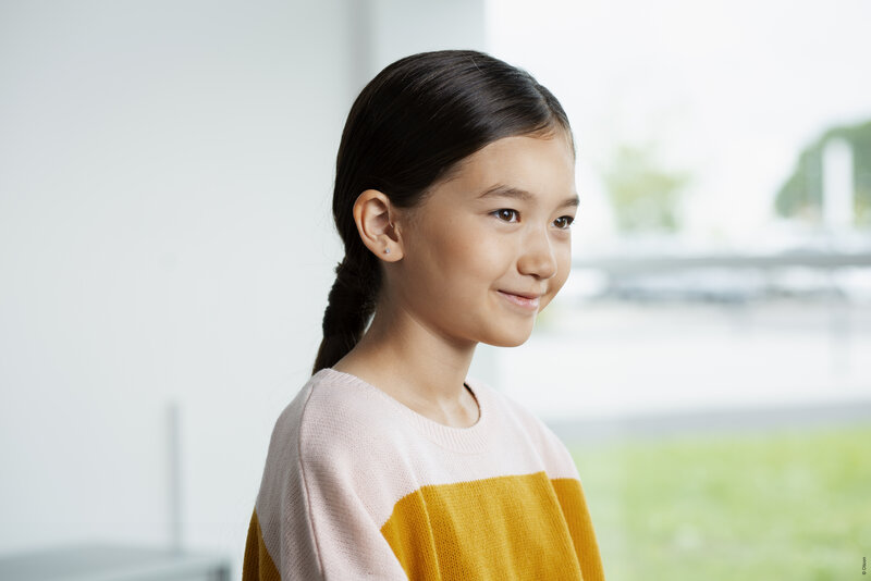 Kind trägt ein Oticon Hörgerät im Ohr